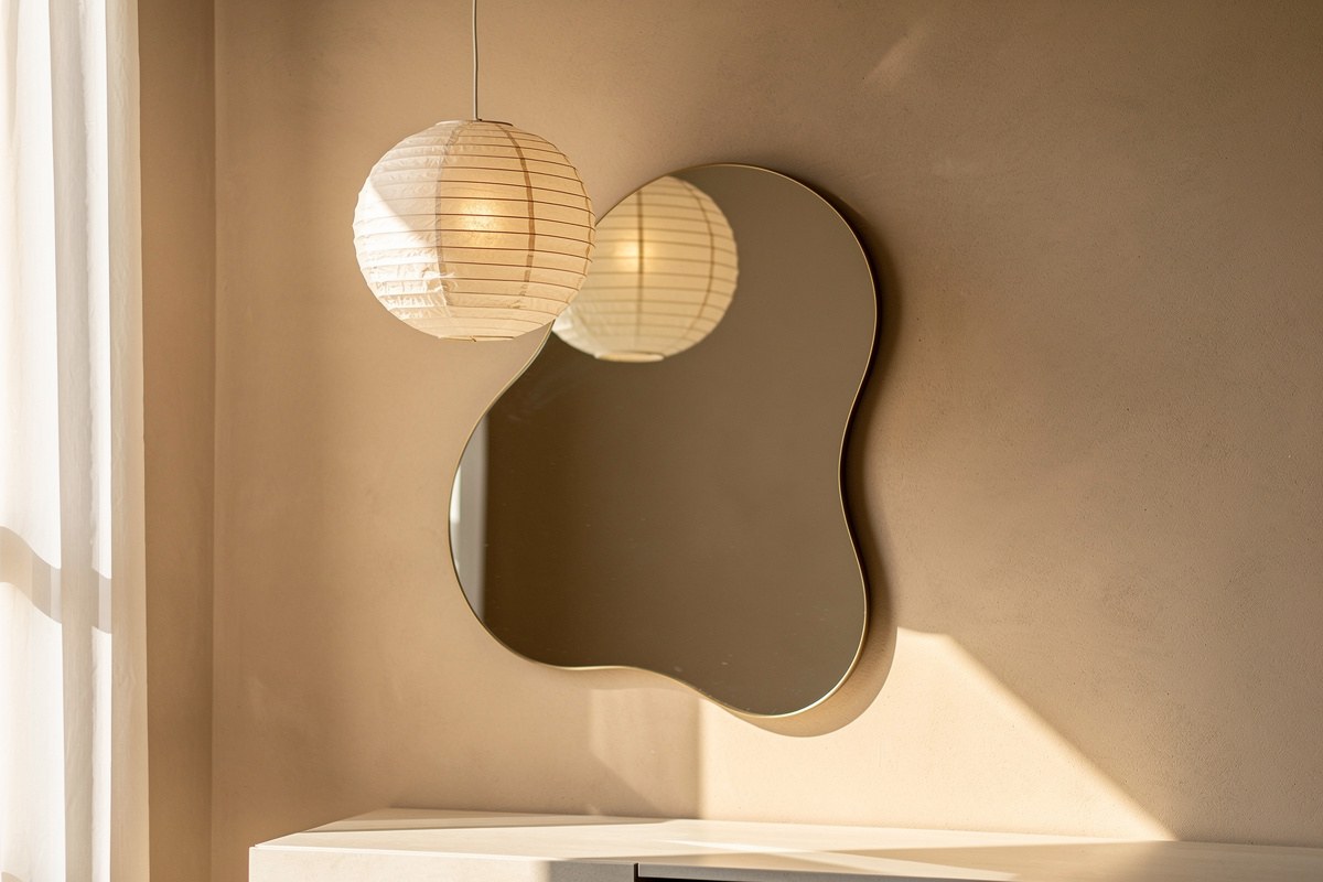 Miroir mural aux contours ondulés et suspension sphérique en papier de riz