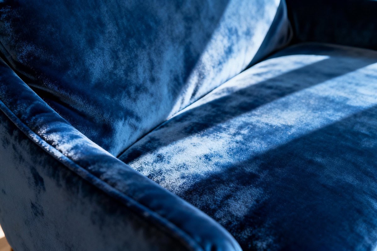 Gros plan sur un velours bleu profond dont les plis révèlent les reflets et le sens du poil