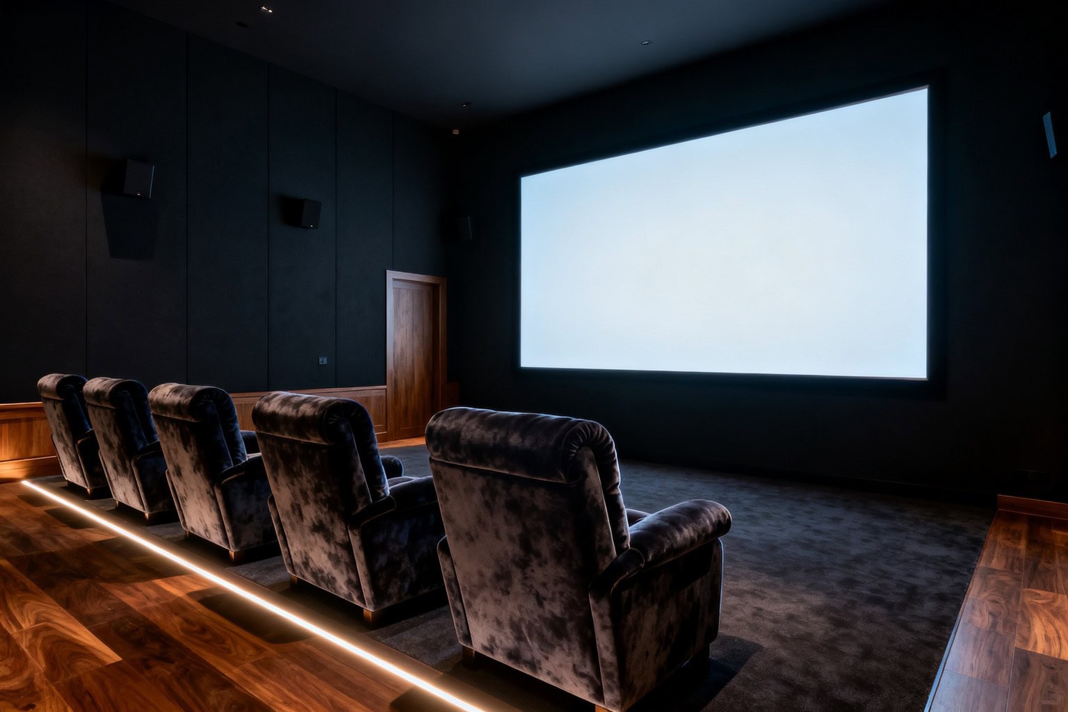 Salle de cinéma privée aux murs sombres, grand écran allumé et fauteuils alignés face à la projection
